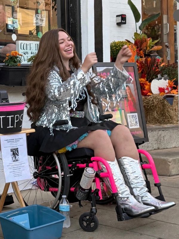 Young woman in wheelchair wearing shiny silver jacket and boots.