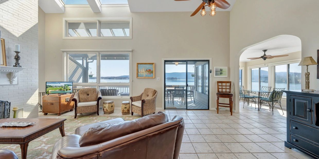 A living room with a skylight, a ceiling fan, and leather furniture