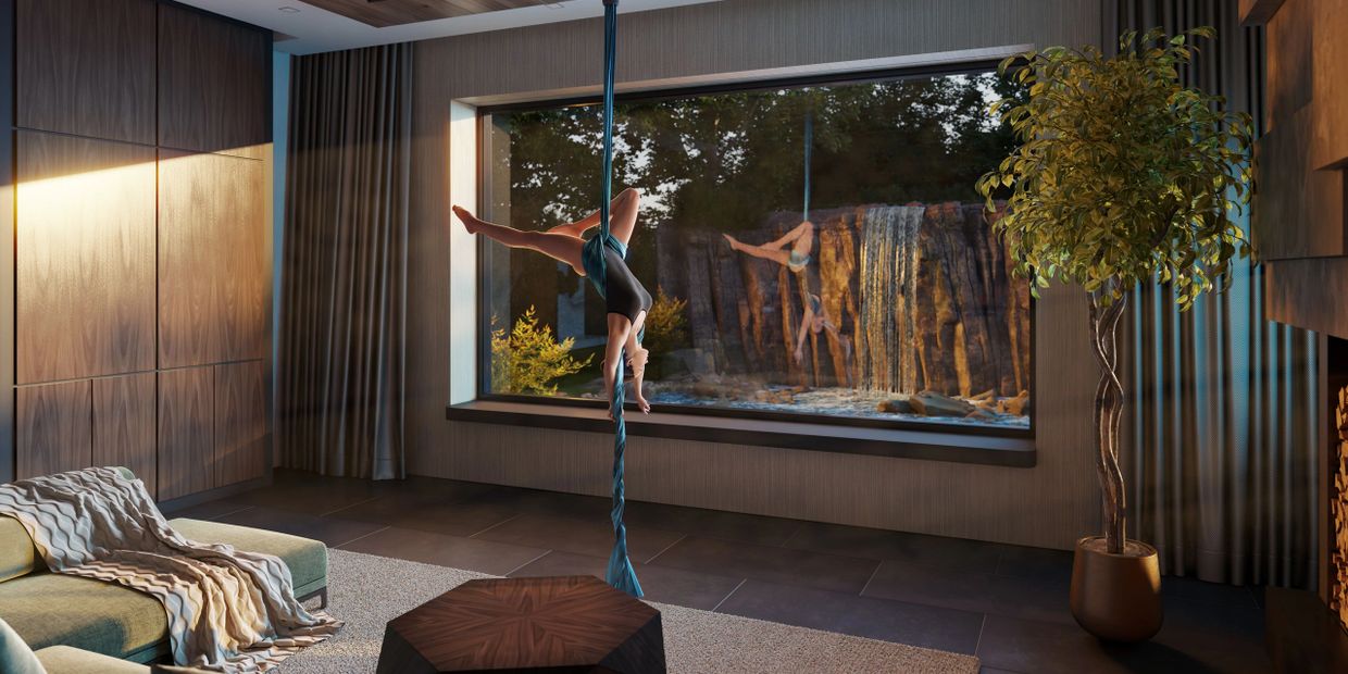 A person performing aerial silk indoors near a large window with a waterfall view.