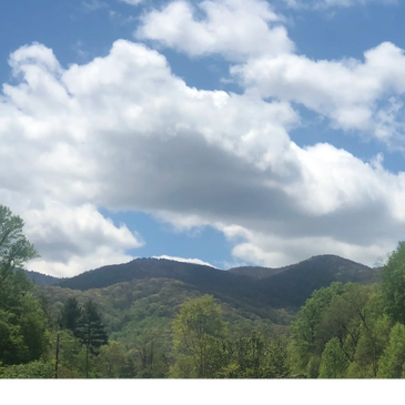 A picture of the Great Smoky mountains, blue sky, and white fluffy clouds. 