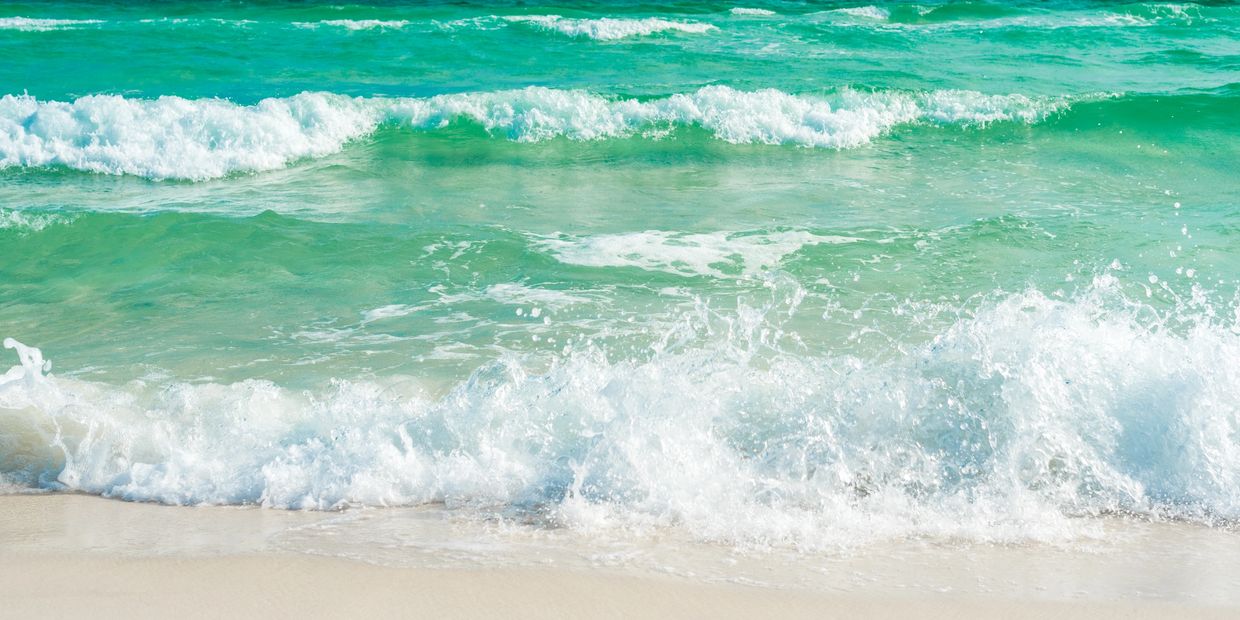 Waves gently crashing on a sandy beach under a clear blue sky.