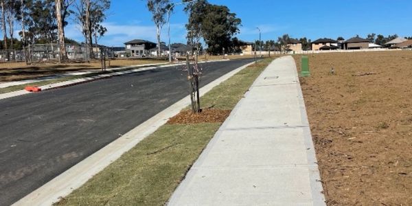 A newly constructed sidewalk and road in a developing residential area.