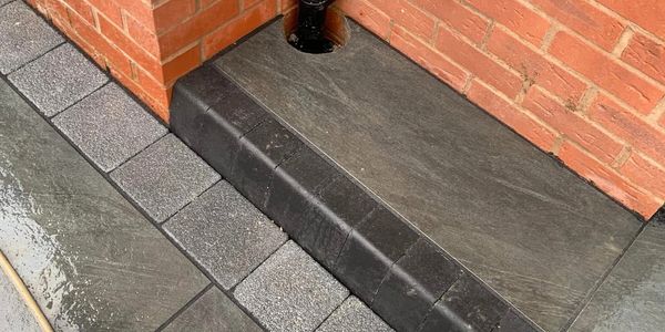 Block paved area with a flagged raised drainage entry.