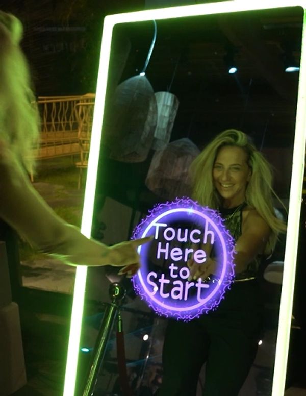 Woman interacting with a glowing touch screen mirror at night.