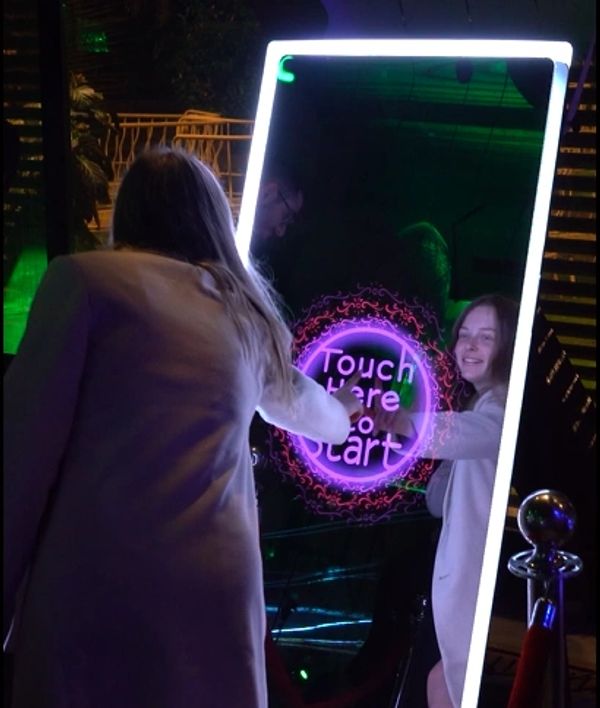 Woman touching an interactive screen that says 'Touch Here to Start'.