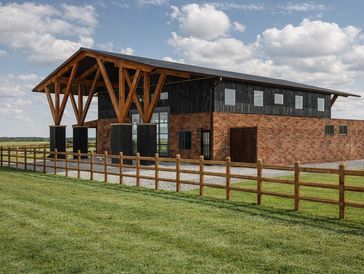 Modern stable building with wood and brick design under cloudy sky.