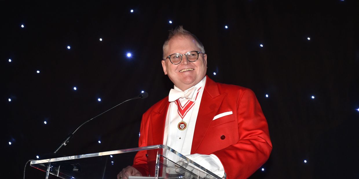 Cheshire toastmaster in red jacket at lectern. Chester toastmaster in red jacket