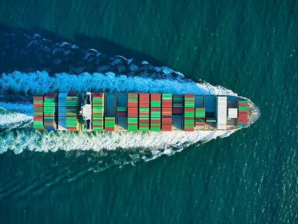 A cargo ship carrying colorful containers sails through the ocean.