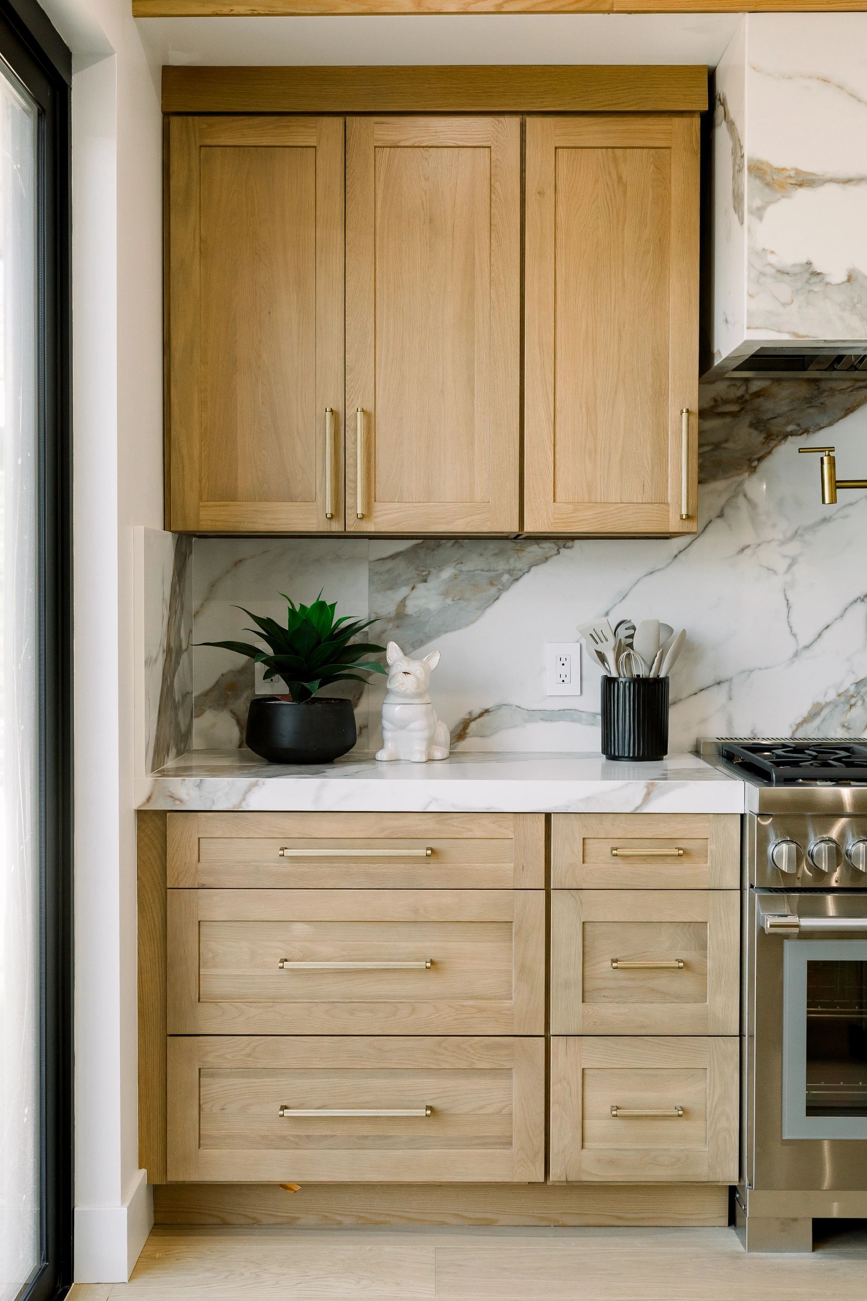 front-facing, light brown, wooden cabinets with white quartz table top. Stovetop found to the right.