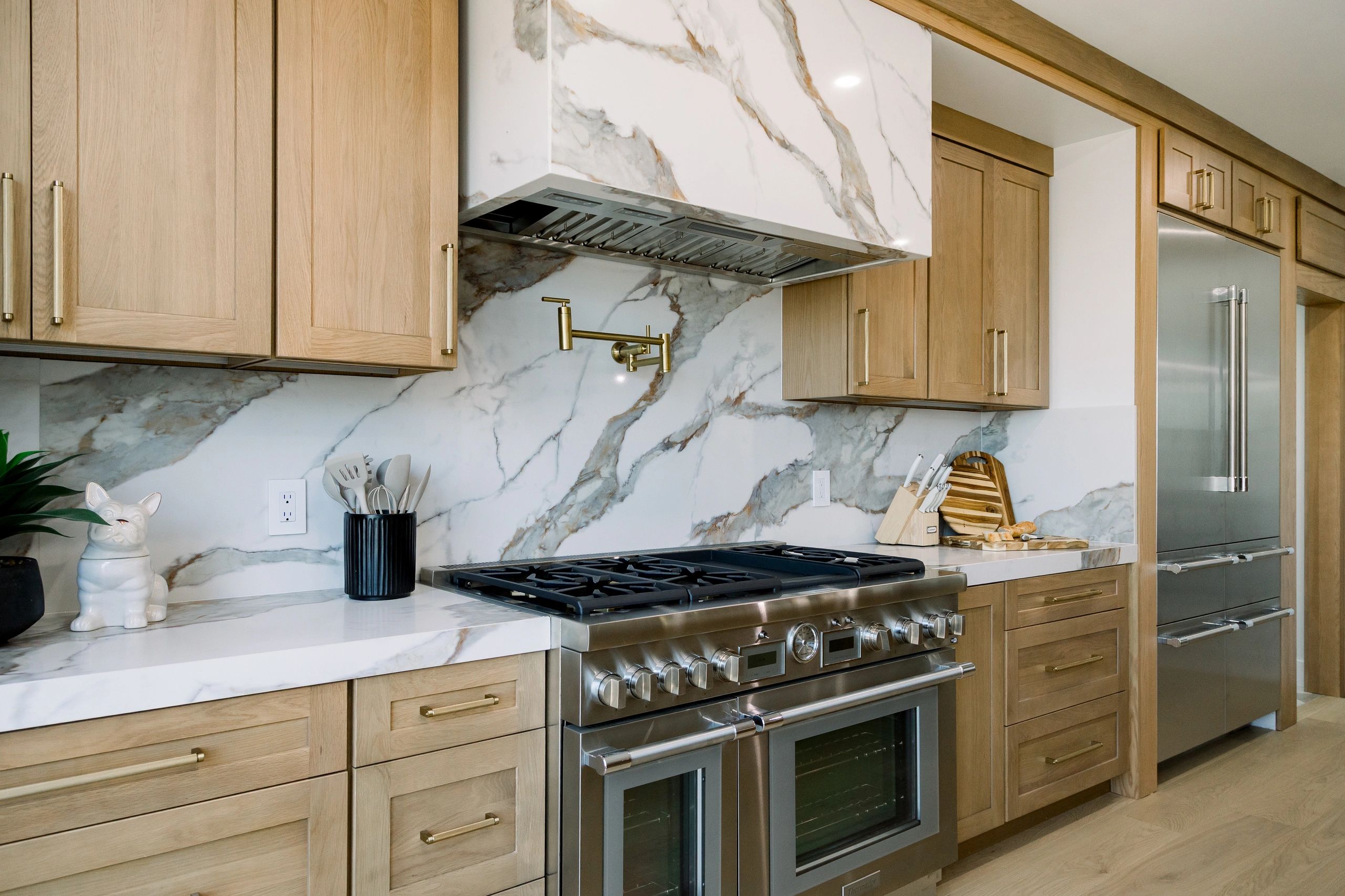Left view of stove top. Utensils found on top of the white quartz countertop and fridge to the right