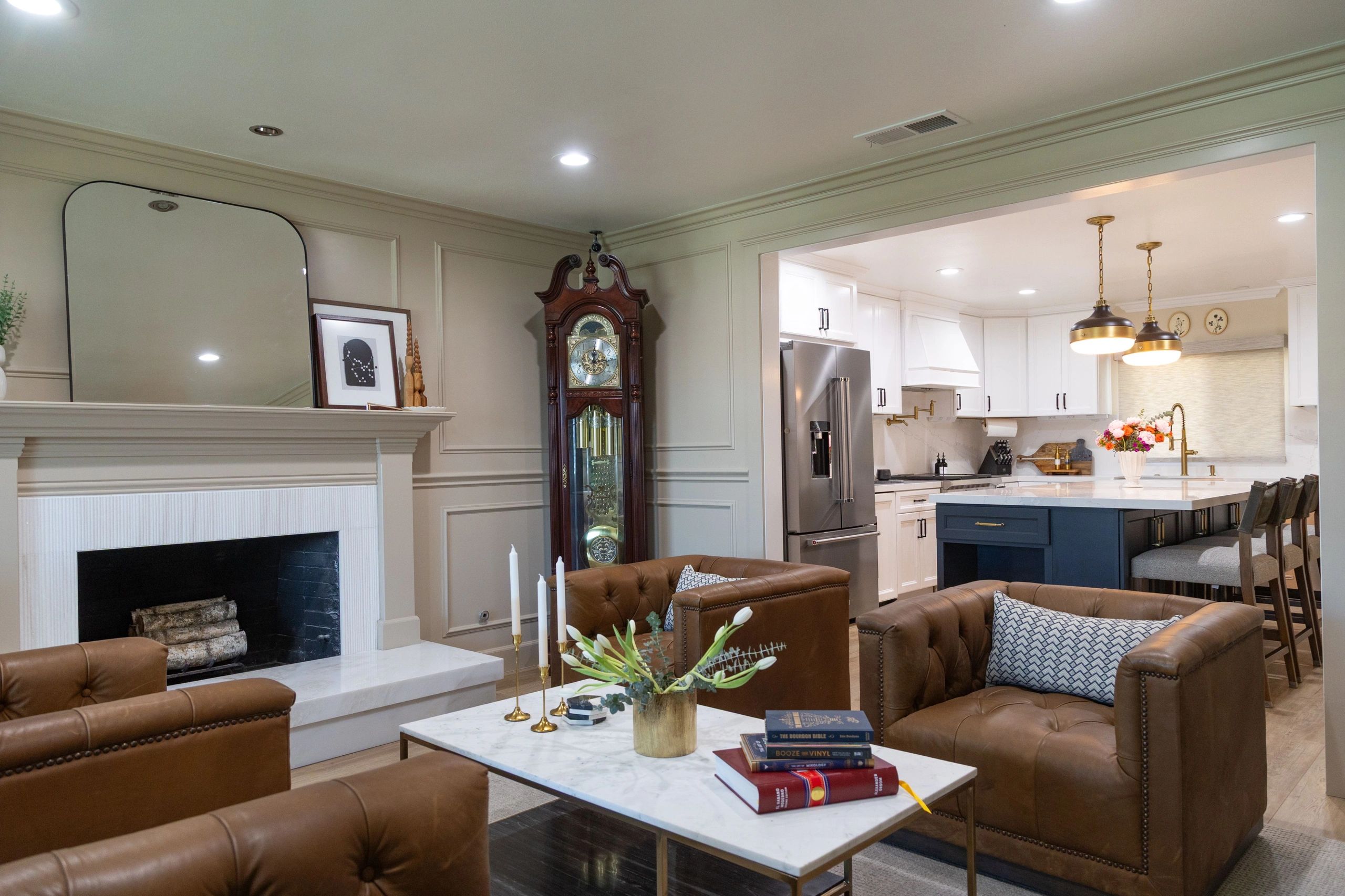 Side view of living room with kitchen shown far right. Long case clock to the right of chimney. 