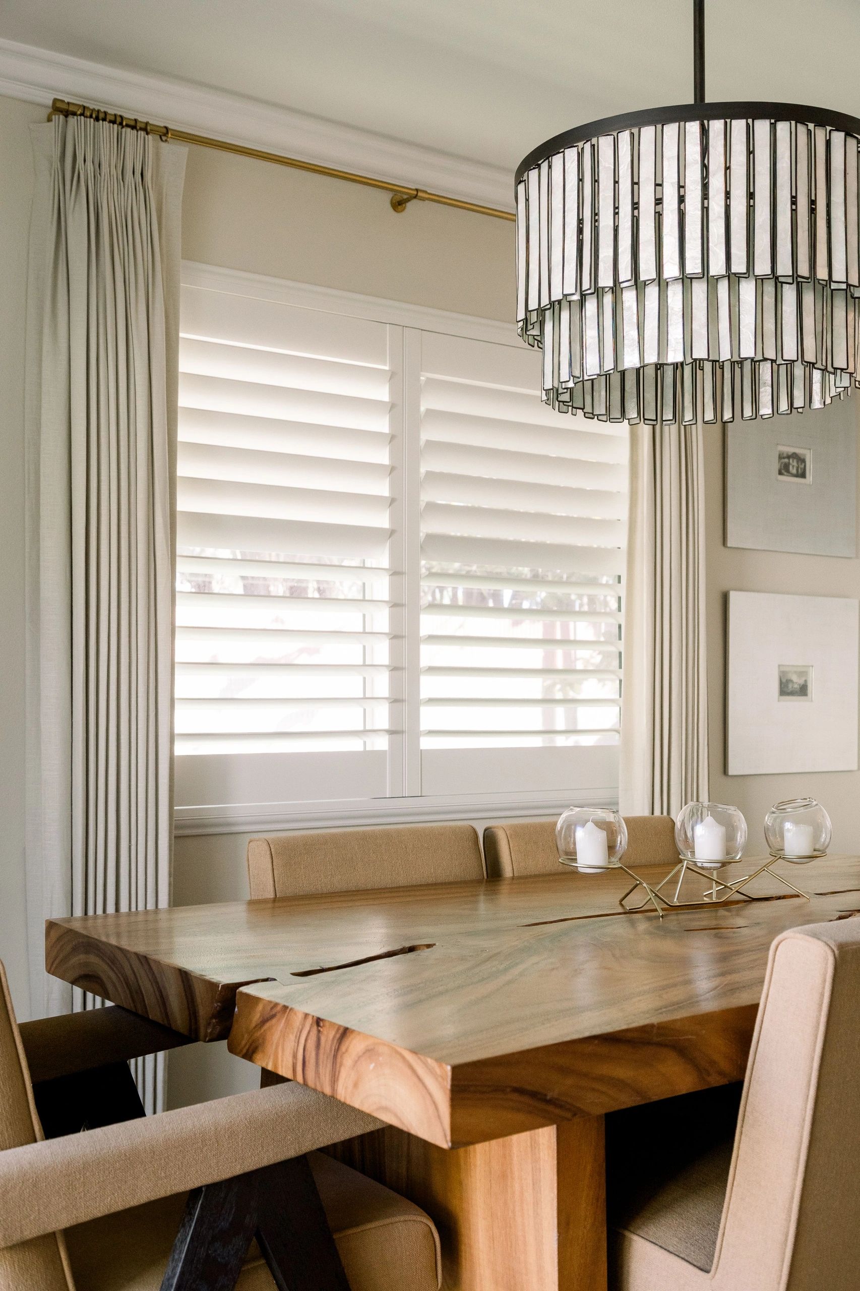 Dining table with a beautiful chandelier above. Brown and white accents can be seen. 