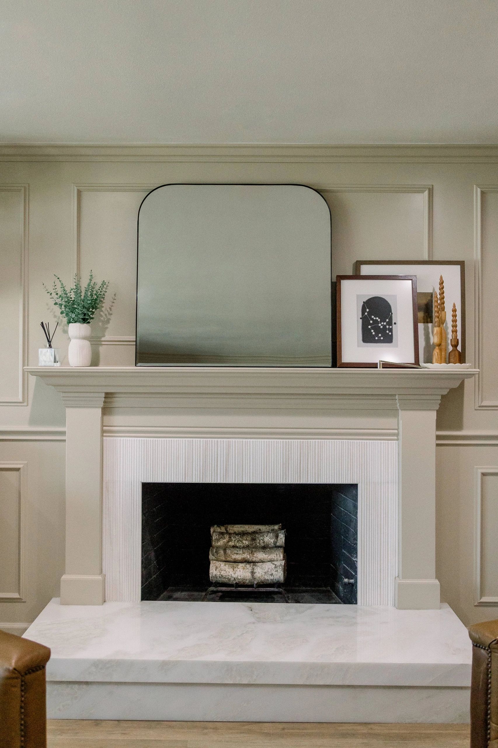 Front view of chimney with decor on mantel. Mirror, picture frames and wooden decor. 