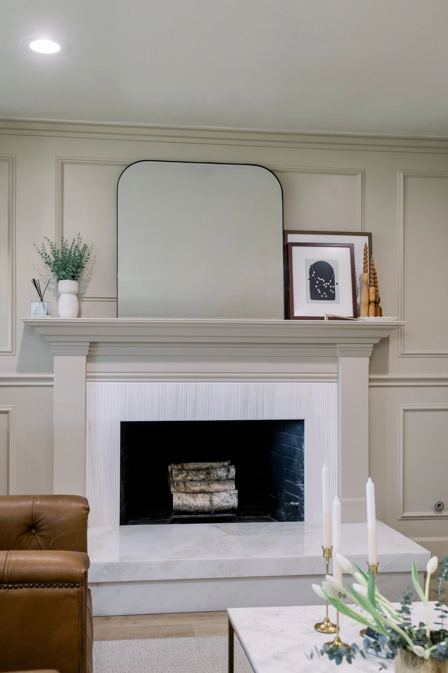 Front view of chimney with mirror on mantel along with picture frames and wooden decor. 