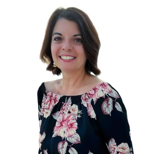 Smiling woman wearing a floral off-shoulder dress against a white background.