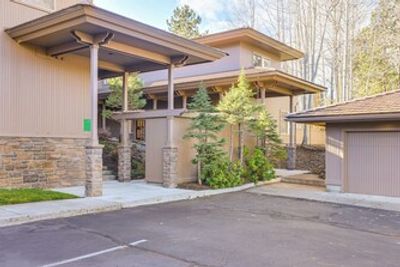 Modern building entrance with stone pillars and surrounding greenery.