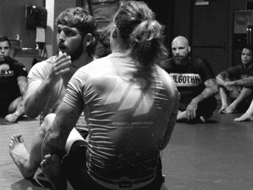 Two men practicing grappling techniques in a martial arts class.
