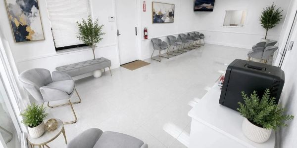 Modern, clean waiting room with gray chairs and plants.