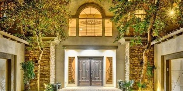 Elegant house entrance illuminated at night with stone and wood details.
