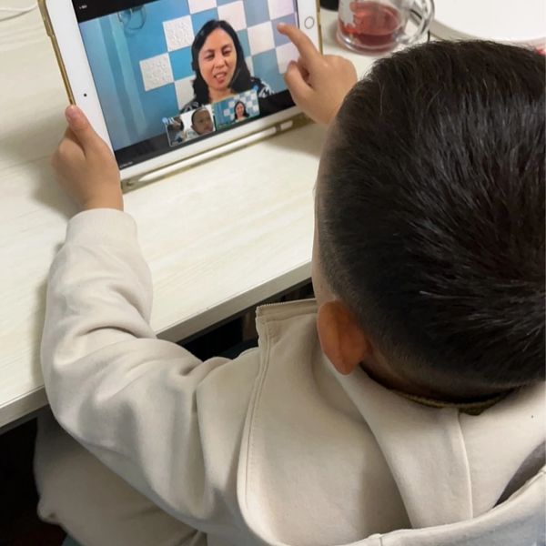 Child engaging in a video call on a tablet with an adult woman.
