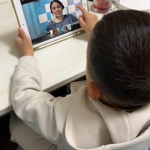 Jasper is attending an online class on a tablet, interacting with Teacher Mary.