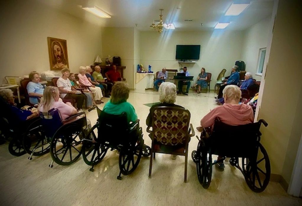 Elderly group sitting in a circle in a communal room.