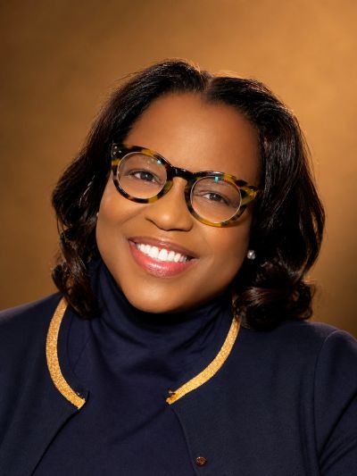 Smiling woman wearing glasses and a navy blue top.