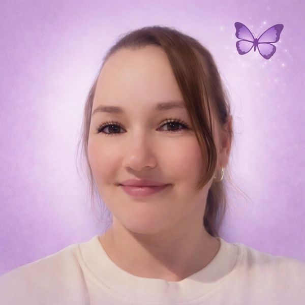 A smiling woman with light makeup and a purple butterfly on a soft purple background.