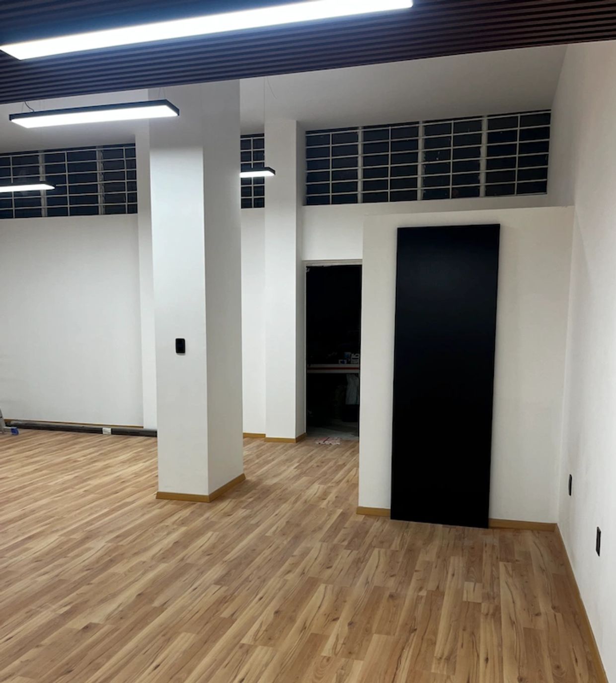 Modern empty room with wooden flooring and white walls.