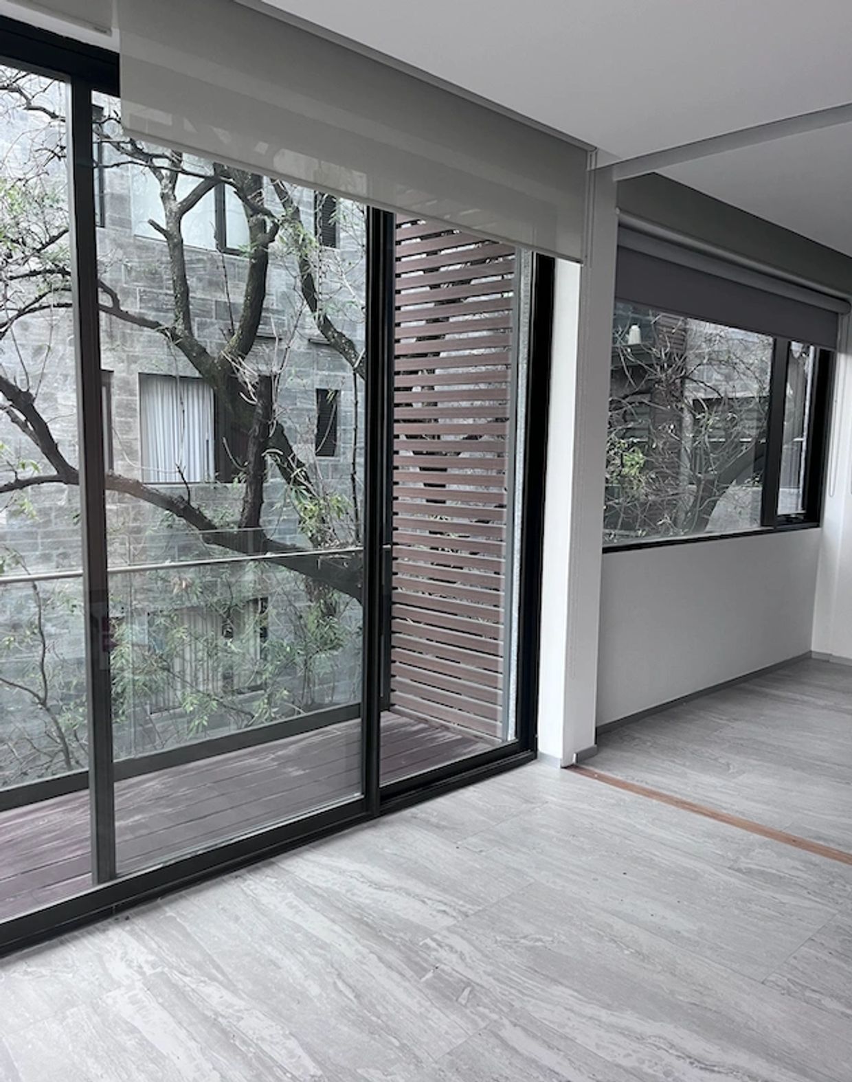 Habitación moderna con suelo gris y grandes ventanales.