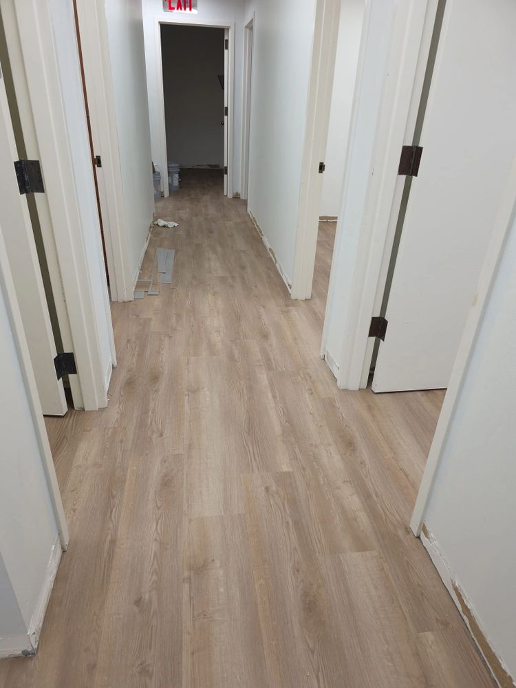 Hallway with new wooden flooring and white walls under construction.