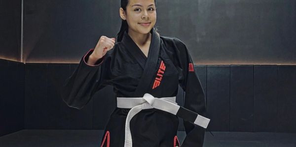 Woman in black martial arts gi with a white belt.
