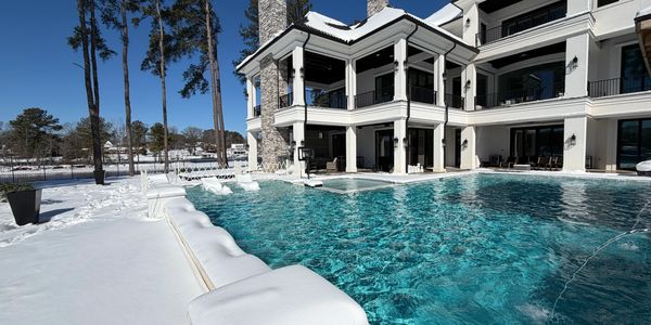Luxury house with outdoor pool surrounded by snow-covered landscape.