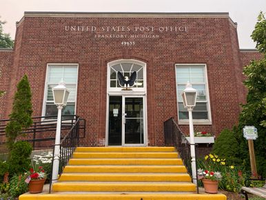 Front entrance of a brick post office with yellow steps.