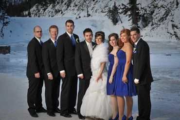 Wedding party poses in snowy outdoor setting.