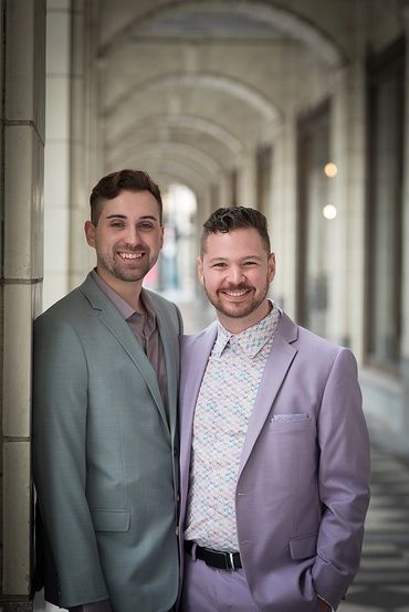 Two men smiling in suits under an archway.