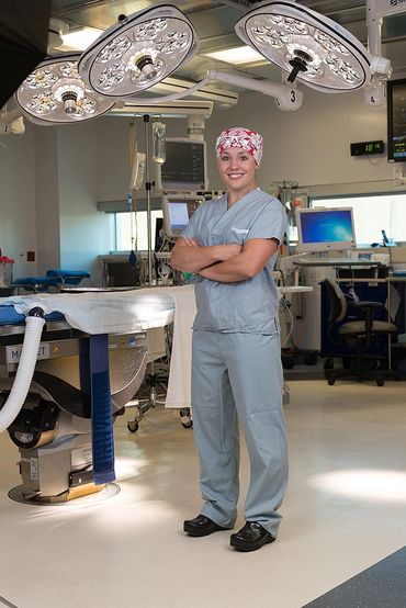 Smiling surgeon in scrubs stands confidently in a modern operating room.