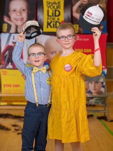 Two children holding hats promoting a kid-focused awareness campaign.