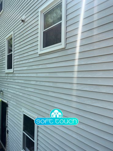 Exterior house wall with vinyl siding and three windows.