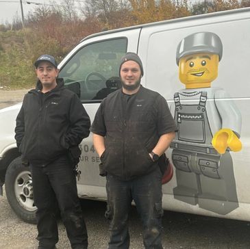 Two men standing in front of a van with a Lego worker graphic.