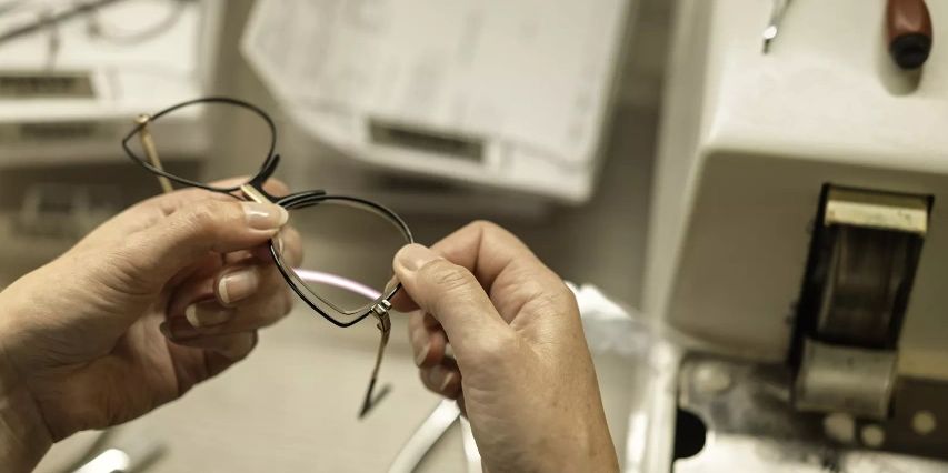 Optical dispenser adjusting the frame, inspecting the lenses for quality, precision.