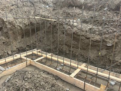 Construction site showing foundation formwork with steel reinforcement bars.