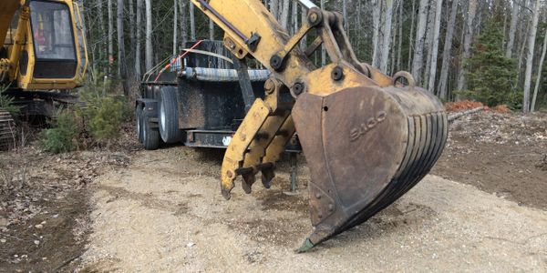 Excavator sitting beside trailer on flattened soil