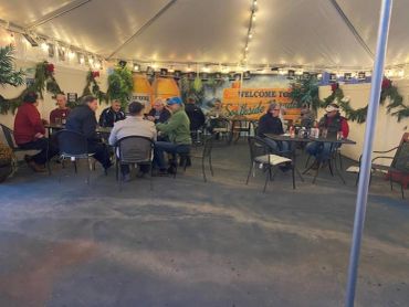 People chat under a decorated tent with string lights.