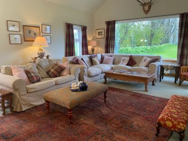 Cozy living room with beige sofas, plaid cushions, and warm lighting.
