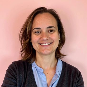 Smiling woman with brown hair against a pink background.