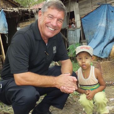 Dan Leaf and a young boy squat together in a village in Vietnam