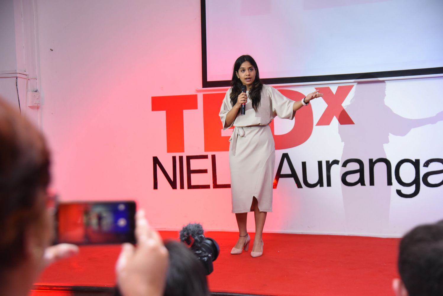Woman giving a TEDx talk on stage.
