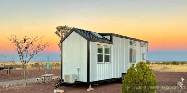 Compact tiny house on wheels at sunset.