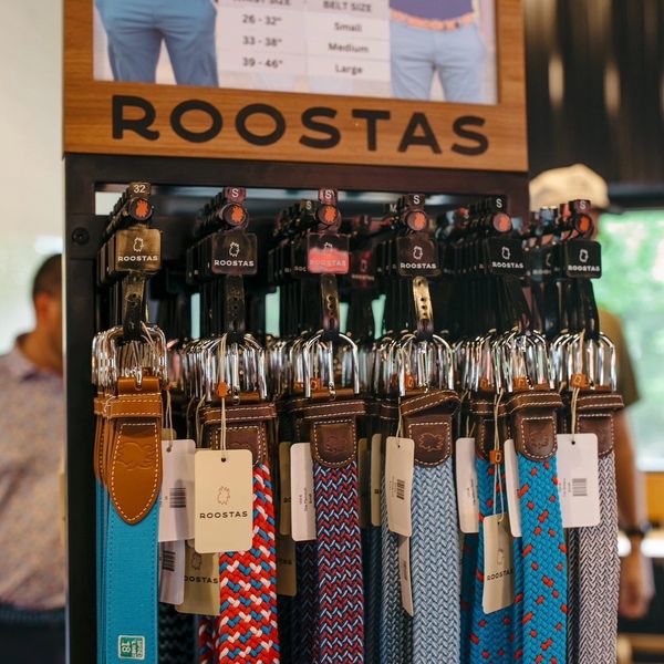 Display of colorful Roostas belts neatly arranged in a store.